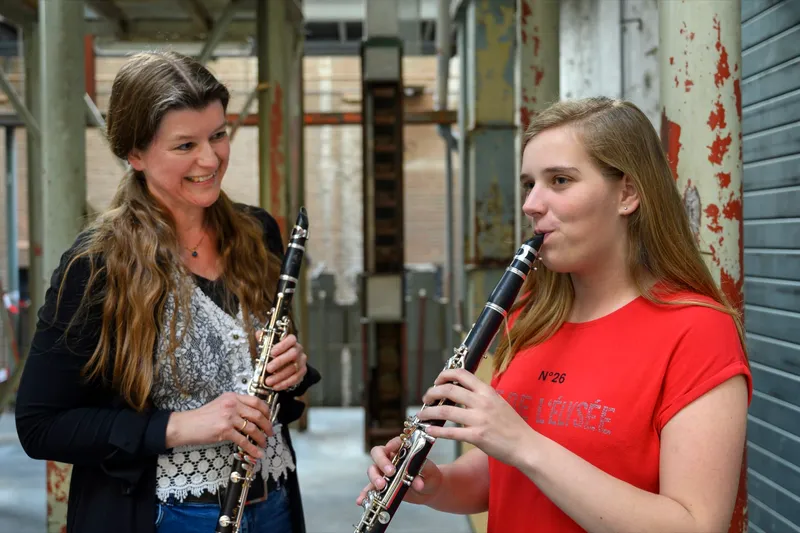 Twee jonge klarinettistes spelen samen in een industriële ruimte